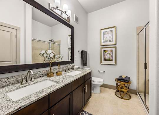 A bathroom with a marble countertop and a large mirror above the sink. at The Royce at 8100, Austin, TX, 78729