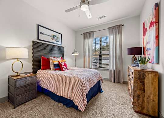 A bedroom with a bed, two lamps, and a painting on the wall. at The Royce at 8100, Austin