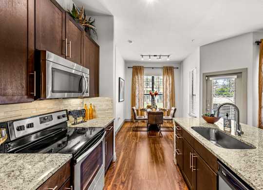 A kitchen with dark wood cabinets and granite countertops. at The Royce at 8100, Austin, TX