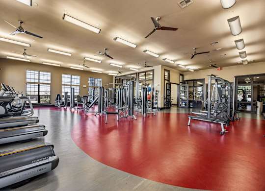 A gym with a red floor and various exercise equipment. at The Royce at 8100, Austin, TX
