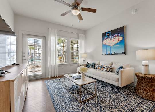 A living room with a white couch, a coffee table, and a ceiling fan.