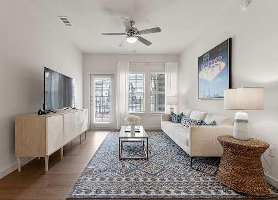 A living room with a white couch, a wooden cabinet, a flat screen TV, a coffee table, and a rug.