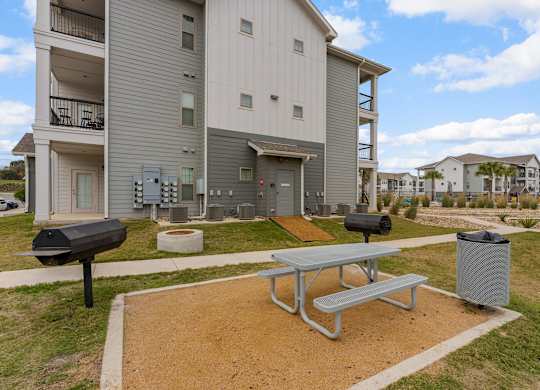 A grey apartment building with a picnic table in front.