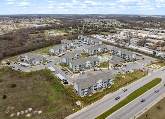 A large apartment complex is surrounded by a parking lot and a road.