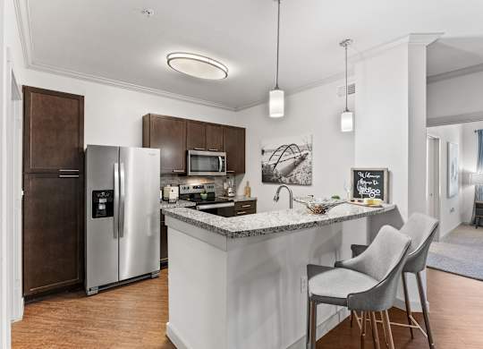 A kitchen with a white island and two chairs. at Bridge at Indigo, Austin, 78717