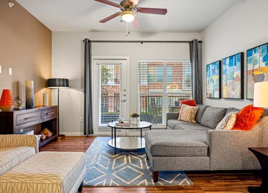 A living room with a grey couch, a coffee table, and a ceiling fan. at Bridge at Southpark Meadows, Austin, TX