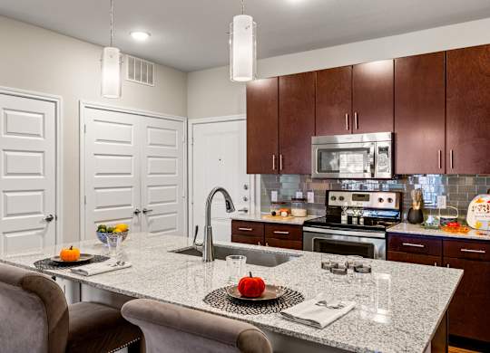 A kitchen with a table and chairs in the foreground and a microwave above the stove. at Bridge at Southpark Meadows, Austin, TX, 78748