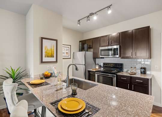 A kitchen with a granite countertop and stainless steel appliances. at Bridge at Southpark Meadows, Austin, TX
