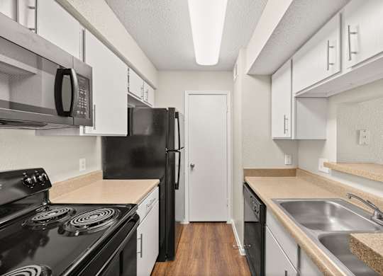 A kitchen with black appliances and white cabinets. at Montecito, Austin, TX
