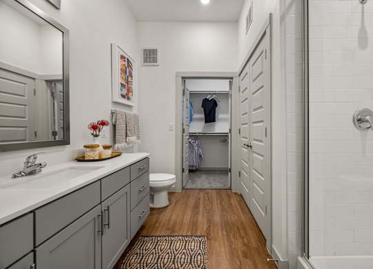 A bathroom with a toilet, sink, and a mirror. at The Haywood Apartments, Austin, Texas