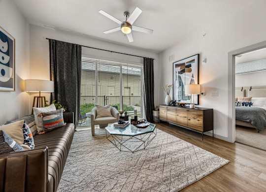 A modern living room with a brown leather couch and a glass coffee table. at The Haywood Apartments, Austin, TX, 78748