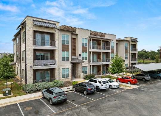 A parking lot with cars and apartment buildings in the background. at The Haywood Apartments, Austin