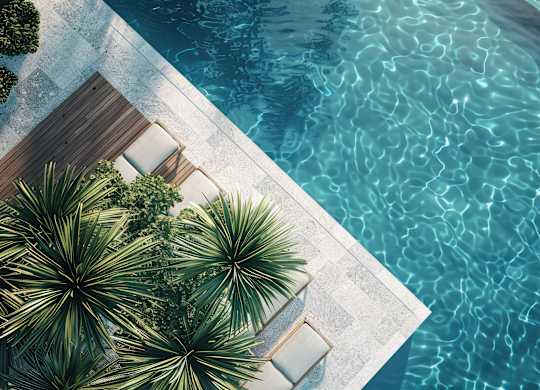 A pool with a wooden deck and palm trees.