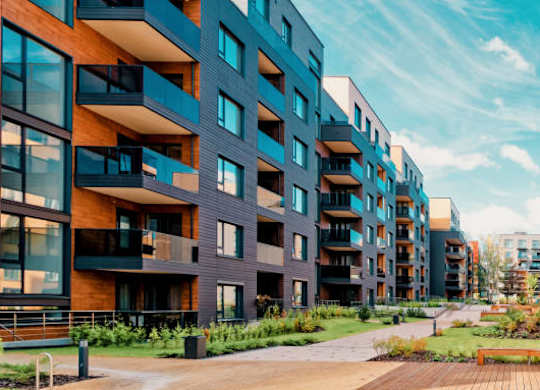 A modern apartment complex with balconies and a wooden walkway.