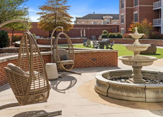a courtyard with a fountain and chairs in front of a building