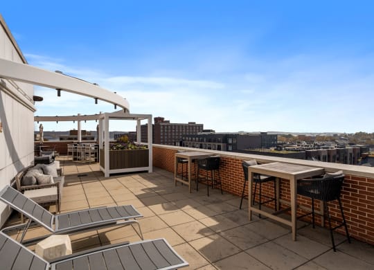a rooftop patio with tables and chairs and a city in the background