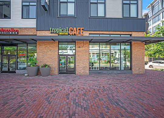 A brick walkway leads to a cafe with a red awning.