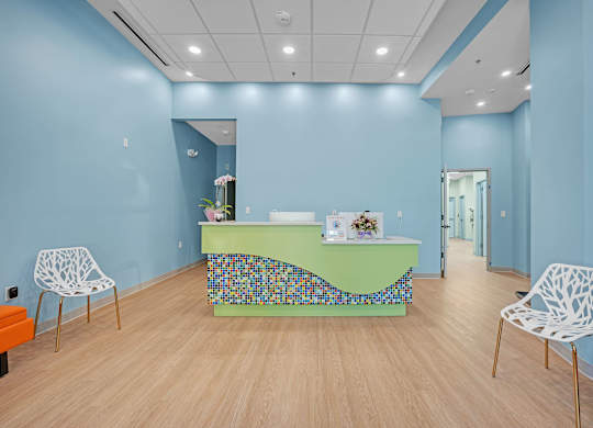 A room with a blue wall and a green table with a mosaic design.