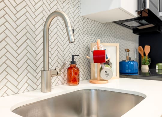 a kitchen sink with a silver faucet and a counter top with a bottle