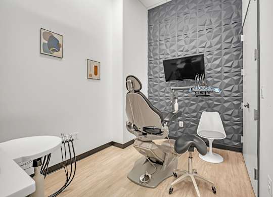 A modern hair salon with a grey patterned wall and a white chair.