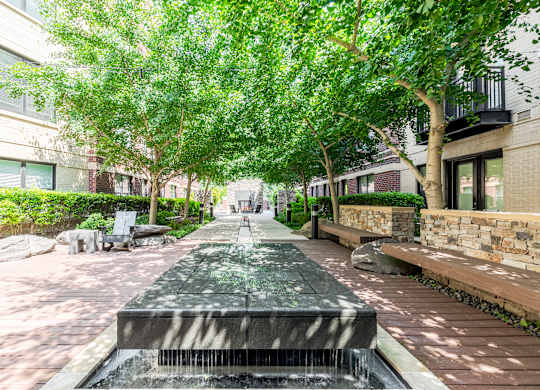 Photo of a peaceful courtyard with water features and lush greenery.