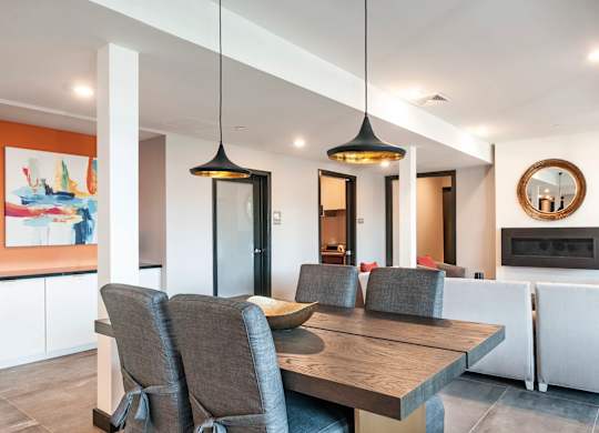 A modern dining room with a wooden table and grey chairs.