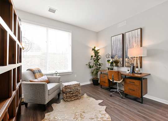 A room with a grey couch, a wooden desk, and a white wall.