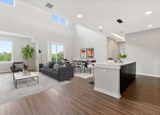 A living room with a grey couch, a white coffee table, and a large window.