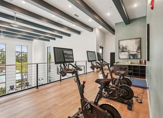 Top level of fitness center with spin bikes and yoga mats at The Crossing