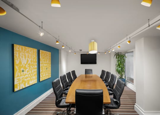 a conference room with a long wooden table and black chairs