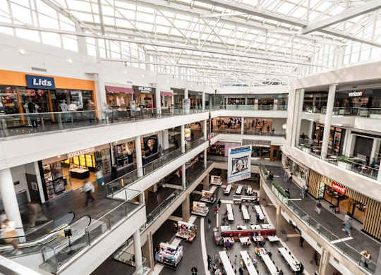 A large atrium of a shopping mall with cars and people.
