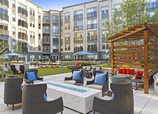 A patio with a table and chairs is surrounded by apartment buildings.