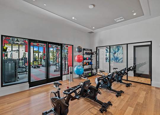 A gym with exercise bikes and a mirrored wall.