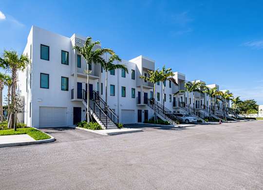 A white building with palm trees in front.