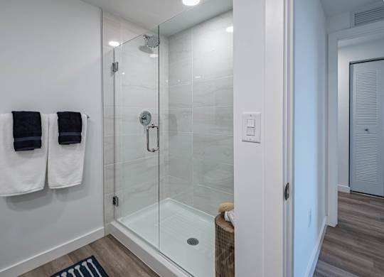 A bathroom with a glass shower stall and towel racks.