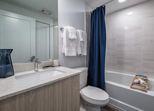 A bathroom with a white toilet, a sink, a bathtub, and a blue shower curtain.