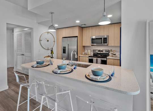 A modern kitchen with a white island and chairs.