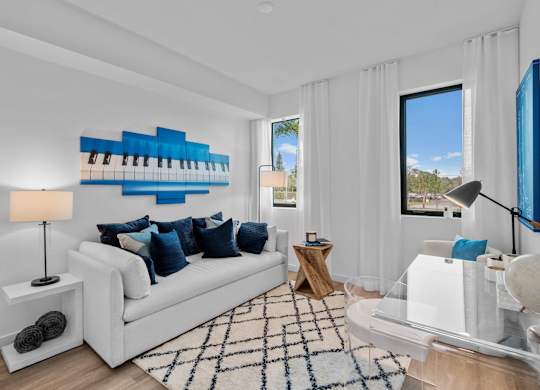 A living room with a white couch, a piano, and a rug.