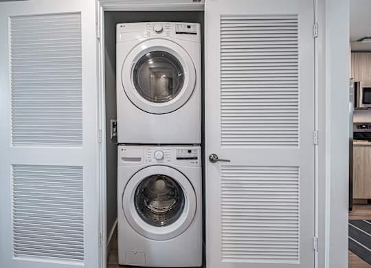 A white washing machine is in a cabinet with a door open.