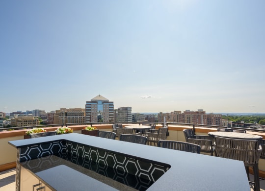 a rooftop patio with tables and chairs and a view of the city