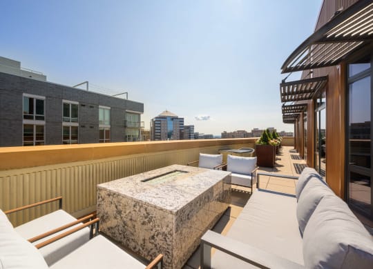 a rooftop patio with couches and chairs and a building in the background