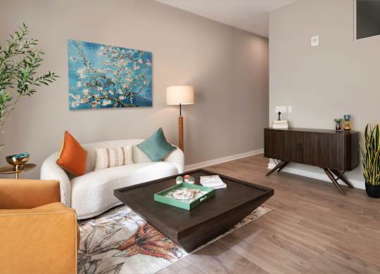 A living room with a white couch, a green pillow, a brown coffee table, and a painting on the wall.