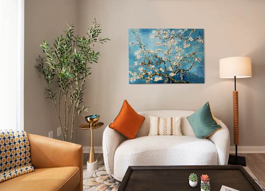 A living room with a white couch, a yellow chair, a green plant, and a painting on the wall.