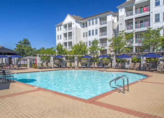 a swimming pool at an apartment complex with umbrellas