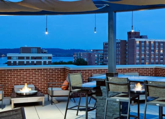A patio with a table and chairs overlooking a cityscape at dusk.