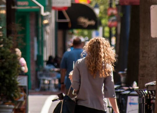 A woman with curly hair walks down a city street.