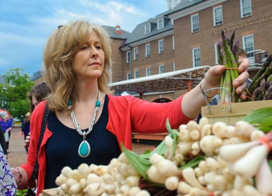 A woman is shopping for vegetables at a market.
