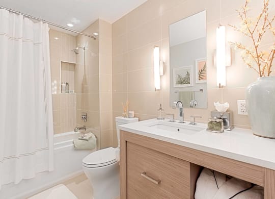 a bathroom with beige tiles and a white shower curtain