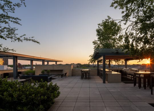a rooftop patio with a firepit and a view of the city at sunset
