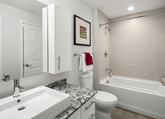 a bathroom with a white bathtub and a white sink with a granite countertop